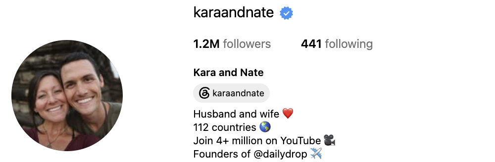 Kara and Nate, an adventure-travel couple, smiling together in a dramatic outdoor destination with an energetic expedition tone.